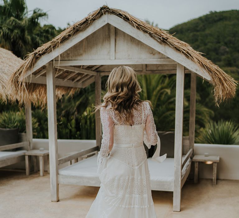 bride in a boho lace wedding dress with long sleeves walking by the pool a pure house ibiza wedding venue