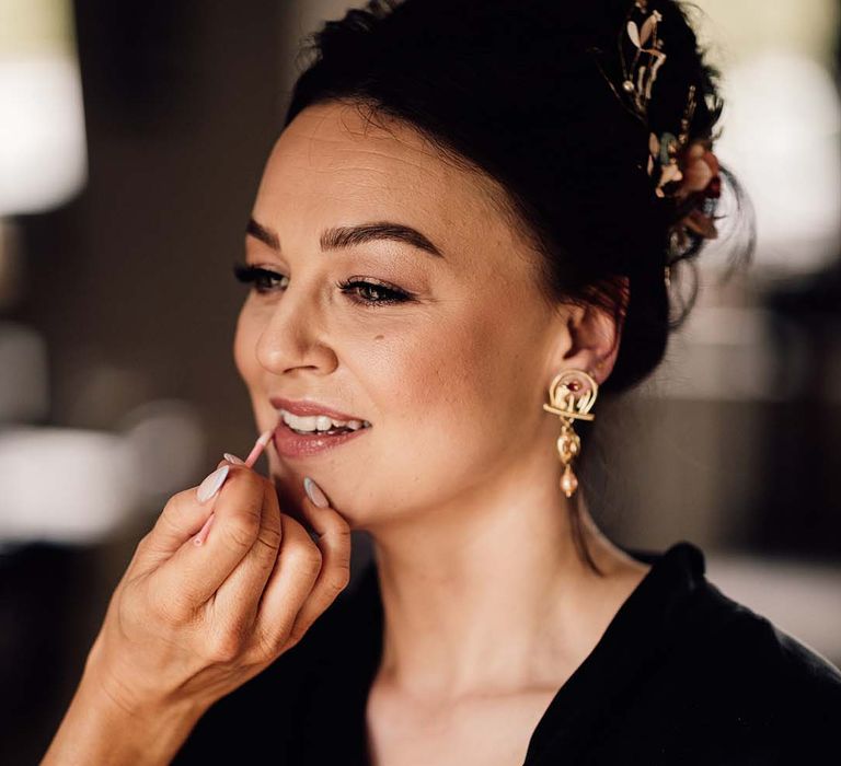 Bride in a black satin robe gets her makeup done for the wedding day 