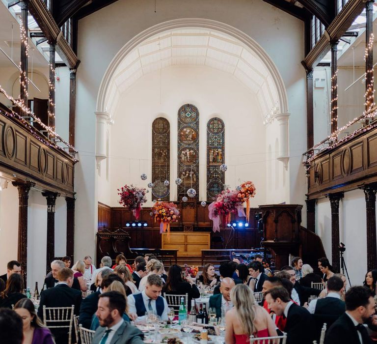 Fabrica Brighton wedding venue reception room with suspended colourful flower arrangements and suspended disco ball wedding decor 