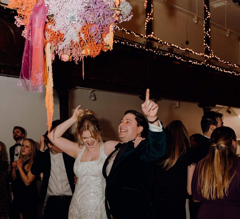 Bride in square neck sequin sparkly reception dress dancing with groom in velvet tuxedo and black bowtie at Fabrica Brighton wedding