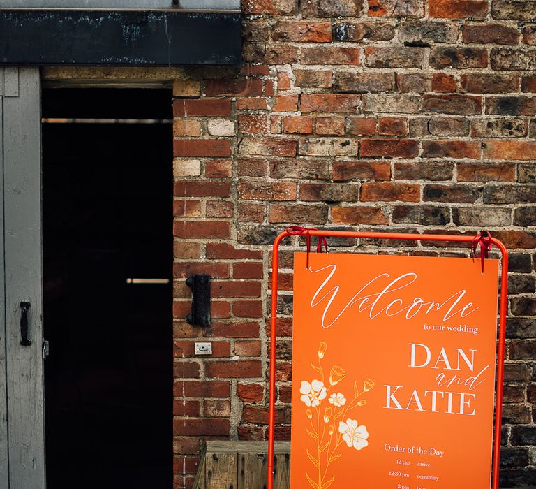 Orange wedding welcome sign with white calligraphy and design 