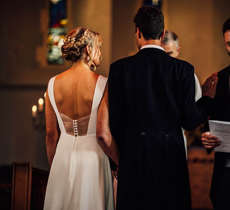 The bride and groom at their church wedding ceremony with a groomsman performing a wedding reading