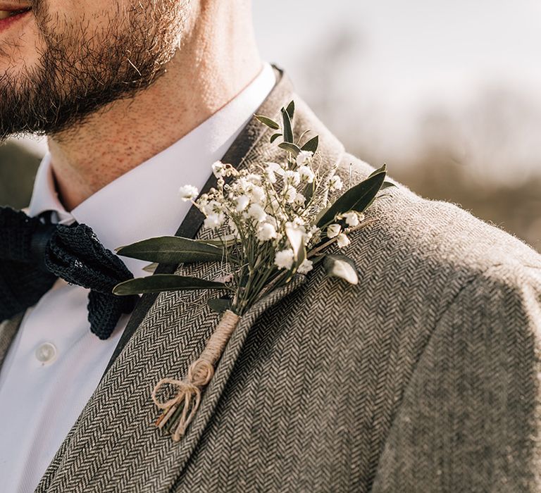 Groom in grey suit with textured navy blue bow tie with gypsophila white floral buttonhole 