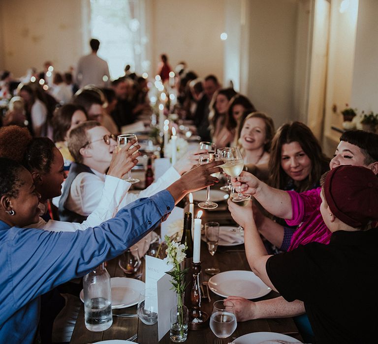 Wedding guests sitting at wedding breakfast make a toast together 