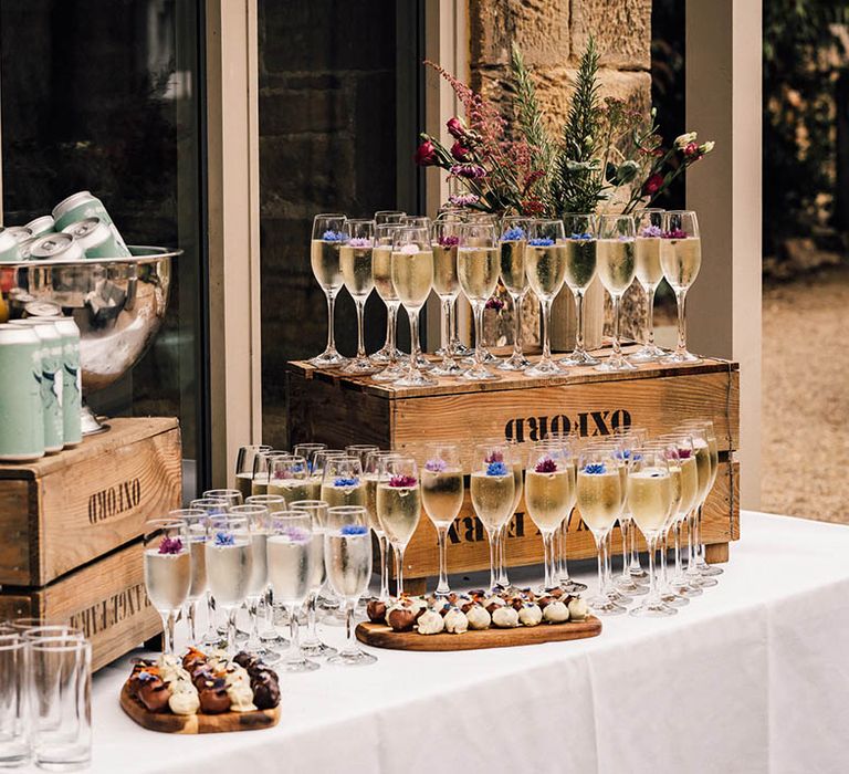 Wedding drinks and favours station with glasses of champagne with purple edible flowers for decoration 