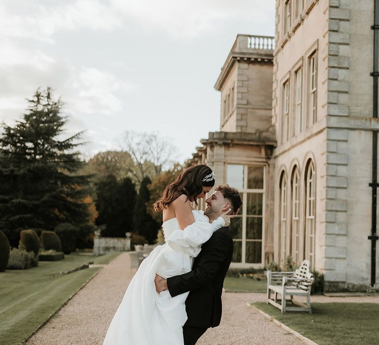 Prestwold Hall in Leicestershire wedding with the groom lifting the bride for couple portrait 