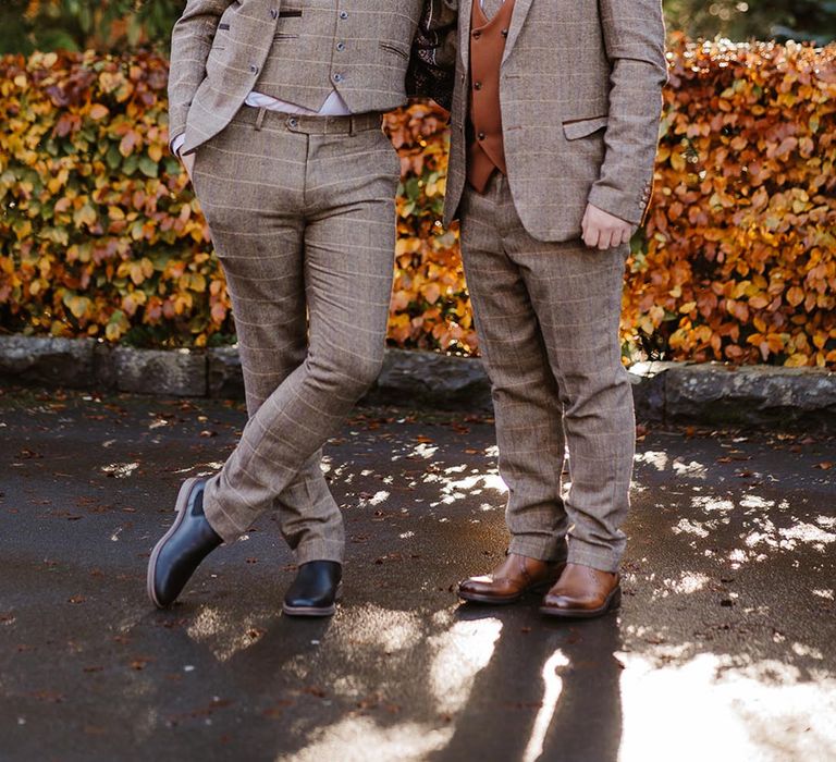 The groom and best man wear three piece brown checkered suits at boho wedding with the groom wearing a tie and brown waistcoat 