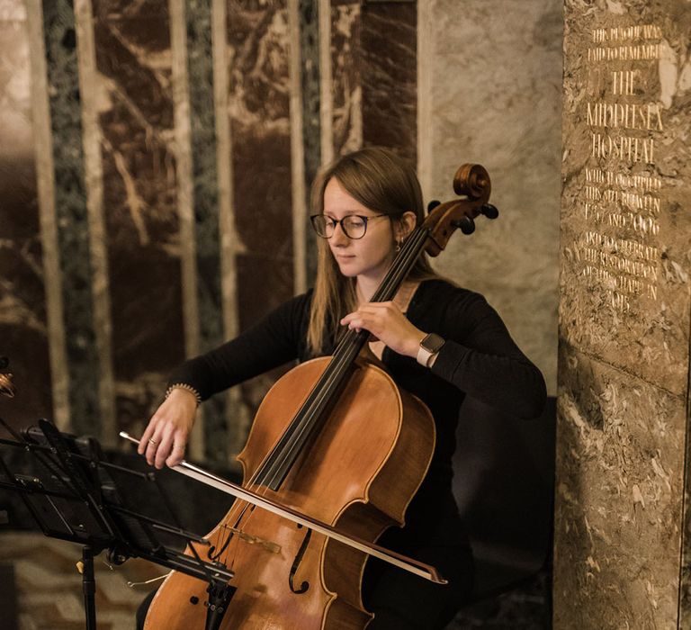 String quartet plays at the wedding ceremony as the bride walks down the aisle 