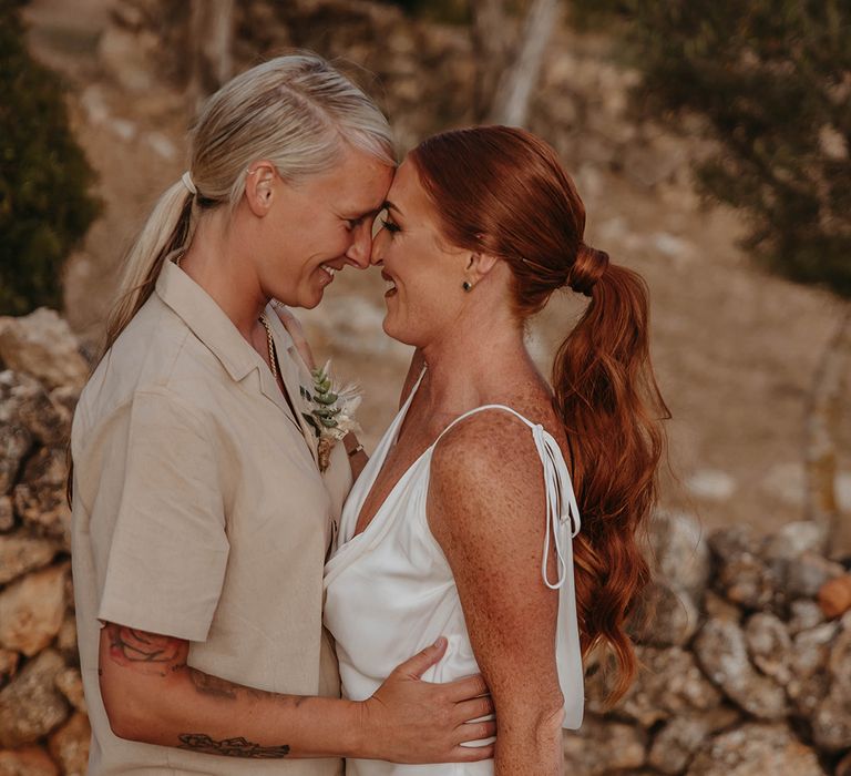 Two brides embrace each other at rustic Ibiza wedding 