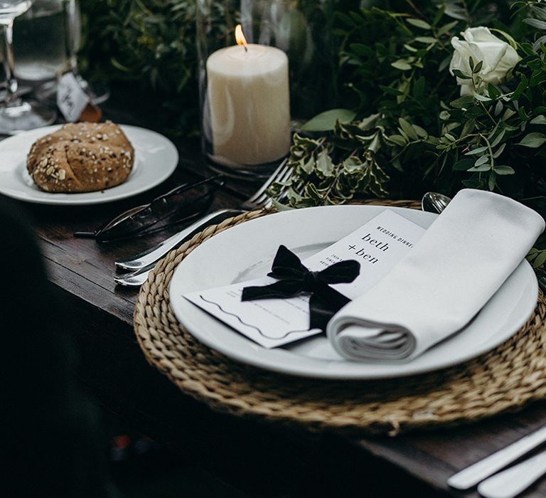 Wicker place mat with white plates and black bow decoration 