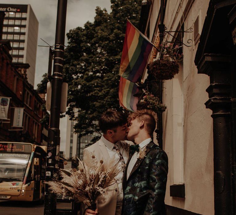 Gay styled shoot with gay couple kissing under a pride flag