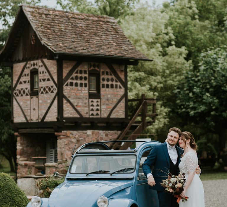 Bride and groom standing next to their convertible wedding car 