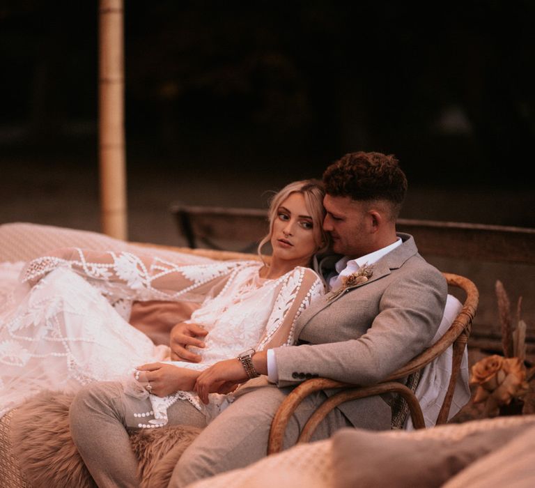 Bride and groom sitting on boho rattan wedding seating