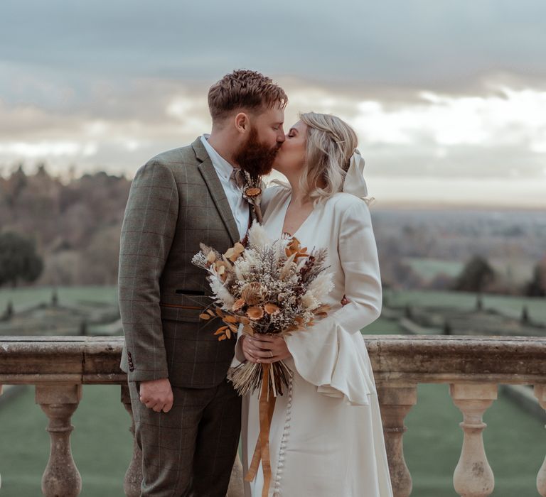 Bride & groom kiss on the balcony of Cliveden House