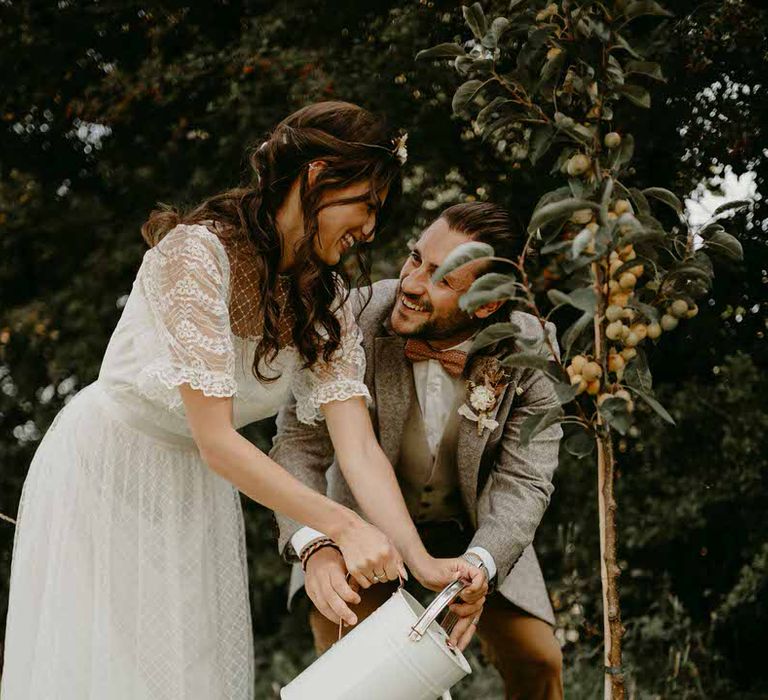 Bride and groom watering a plant at their sustainable wedding