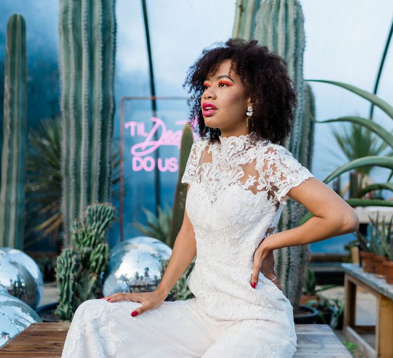 Bride sitting in White Lillian West bridal jumpsuit at Urban Jungle Suffolk