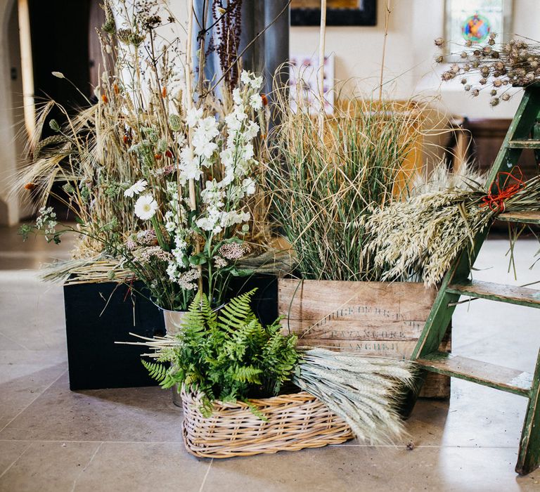 step ladder, wooden crates and wicker baskets filled with wildflower arrangements 