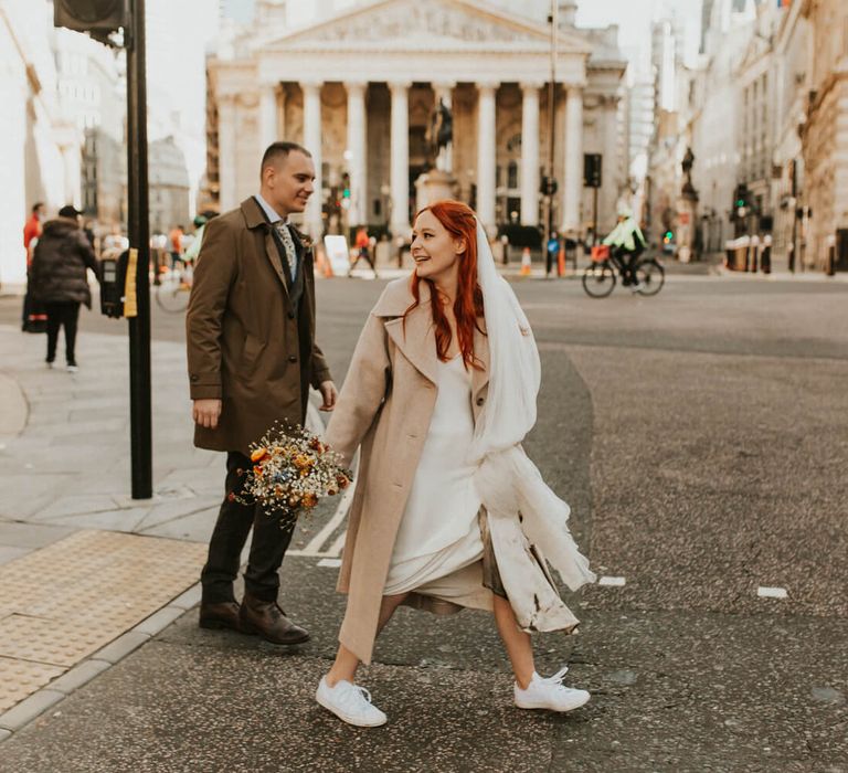 Bride and groom crossing busy London street at their London elopement wedding 