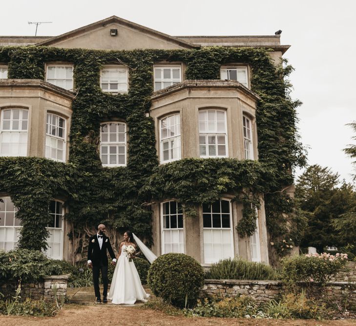 Bride and groom portrait outside their wedding venue, Northbrook Park, with the bride in a Oleg Cassini wedding dress and the grooms wearing a velvet tuxedo 