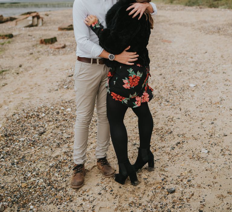 Groom-to-be embracing is Fiancee in a black faux fur coat on Cudmore Grove, East Mersea each in Essex