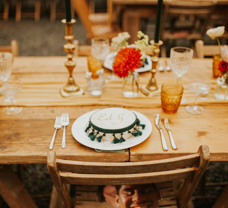 Moroccan and autumn themed wedding decor at Anran wedding venue with wooden tables, tambourine favours and coloured glassware 