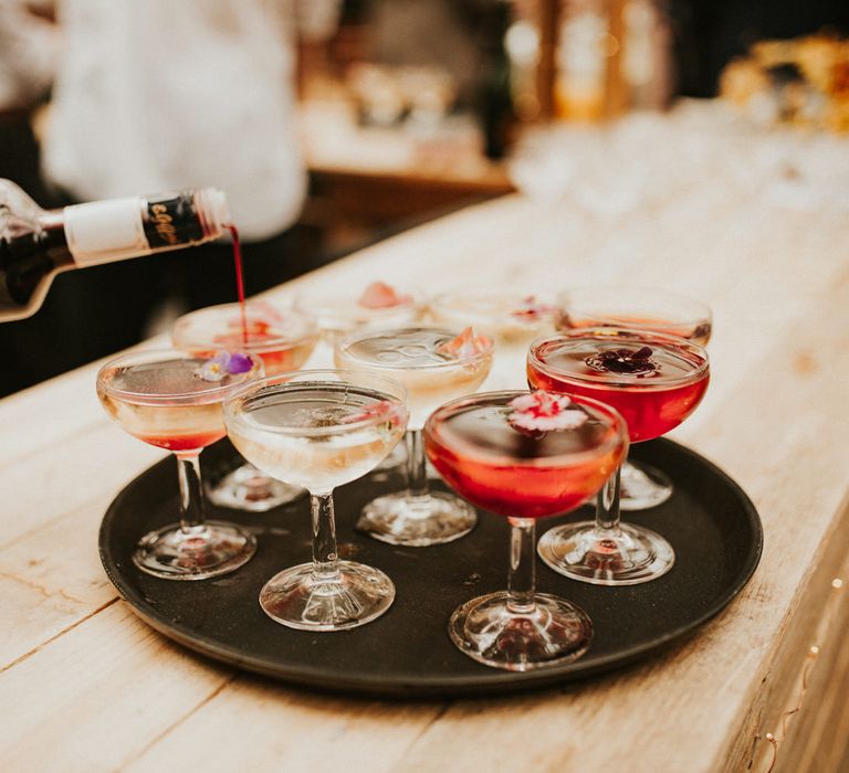 Tray of cocktails in coupe glasses with edible flowers