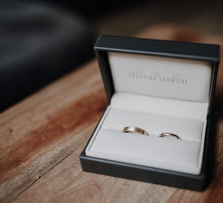 Bride and groom's wedding rings in black and white box on wooden table