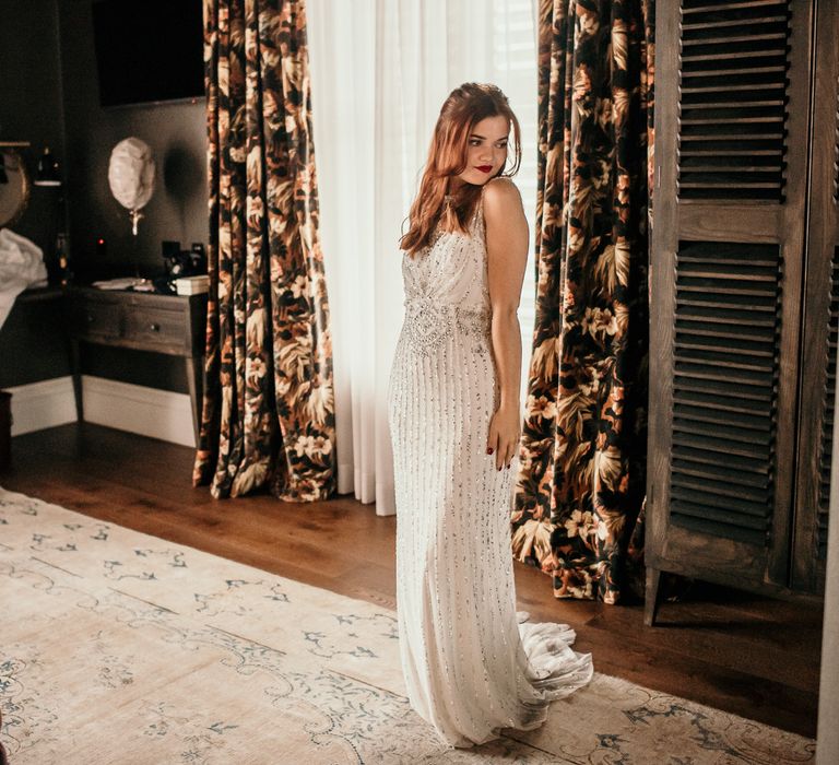 Bride poses in front of the mirror wearing embellished lace gown