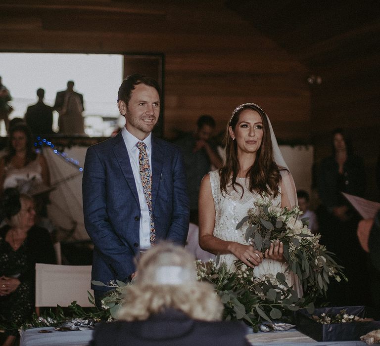 Bride & groom stand at the altar during wedding day on the beach