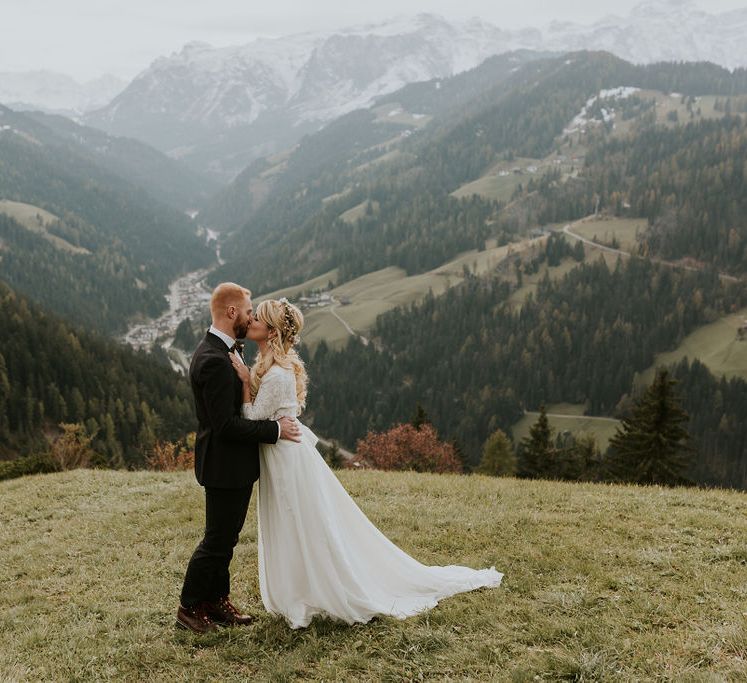 Bride in a Carla Spose wedding dress kissing her groom up the Dolomites mountains 