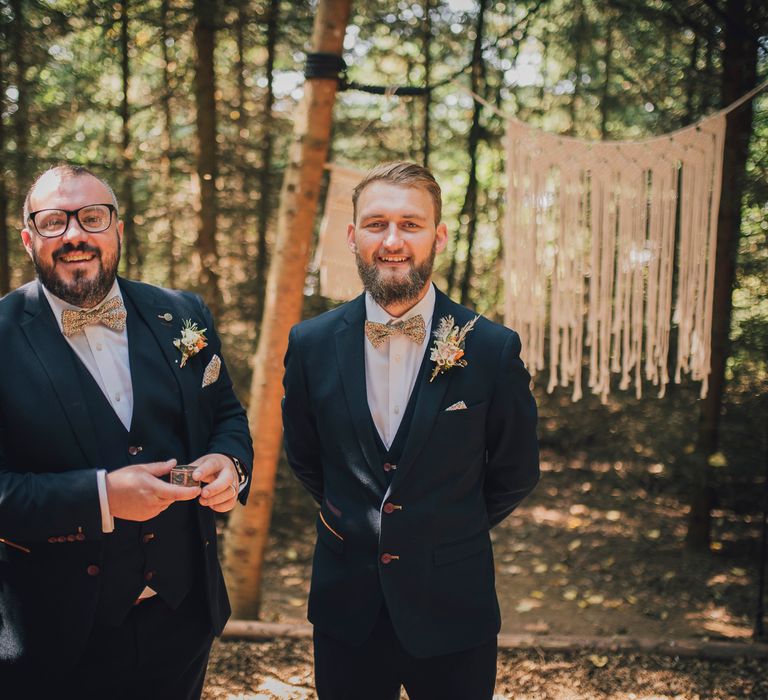 Groom waits with groomsmen in woodland before wedding ceremony