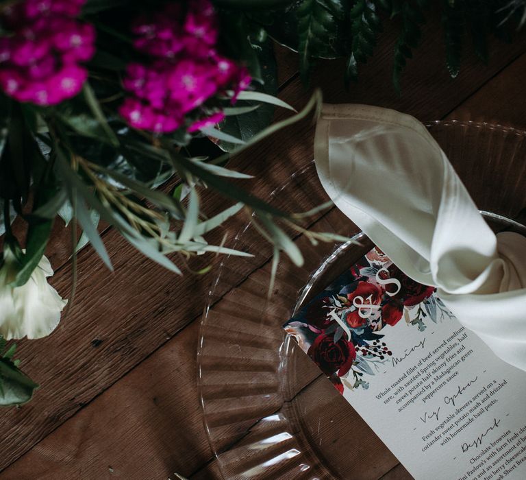 Moody romantic wedding table decor with pink and red flowers and floral menu