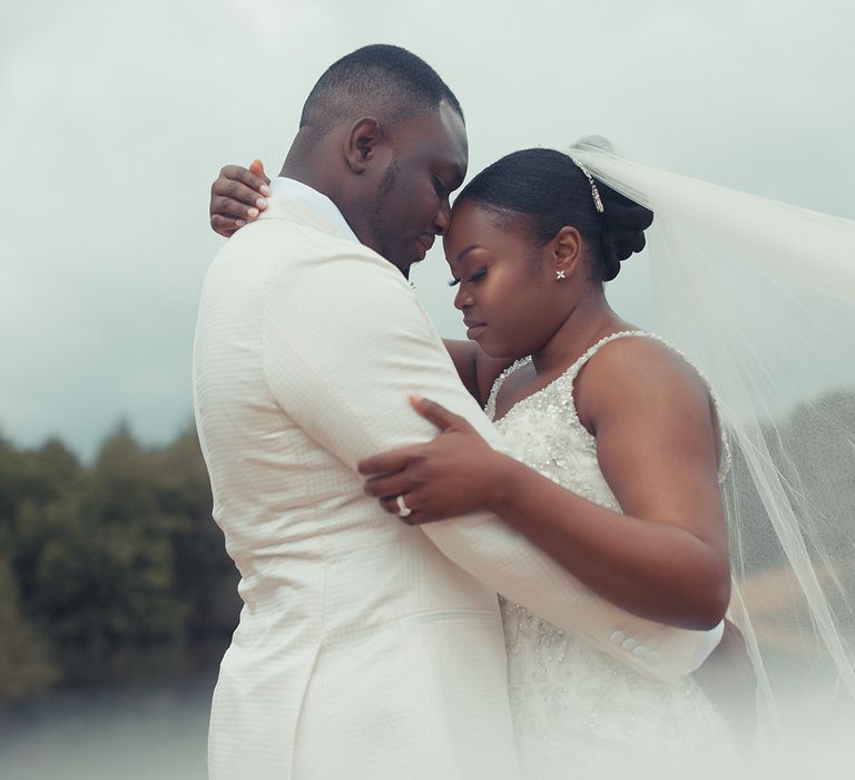 Bride & groom embrace outdoors within fields on their wedding day