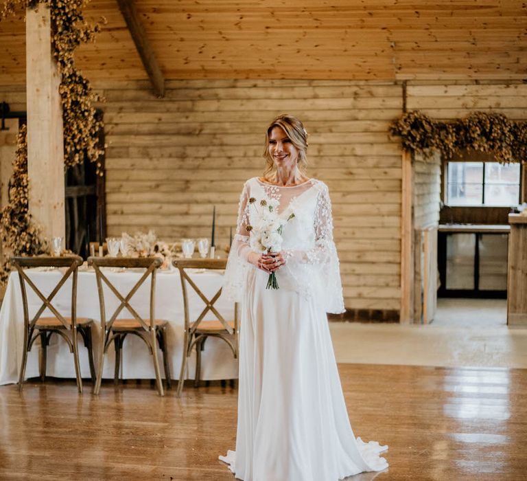 Rustic luxe bridal look with embroidered bell sleeve wedding dress and small white flower bouquet