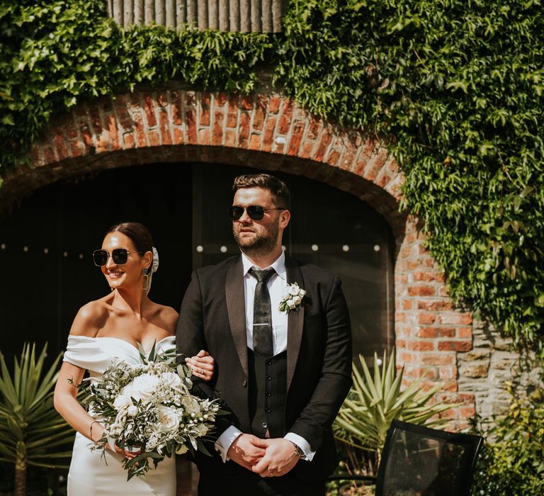 Bride and groom in sunglasses with white flower bouquet