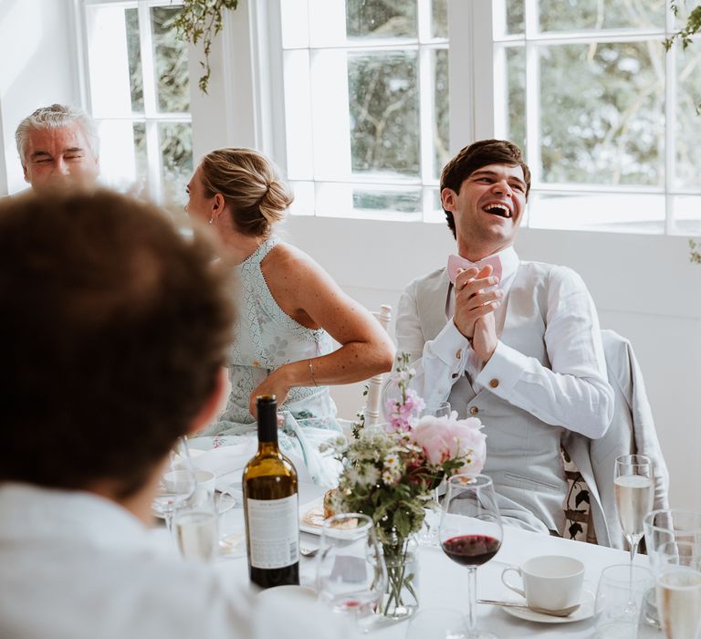 Groom laughs during wedding reception on the day of his wedding