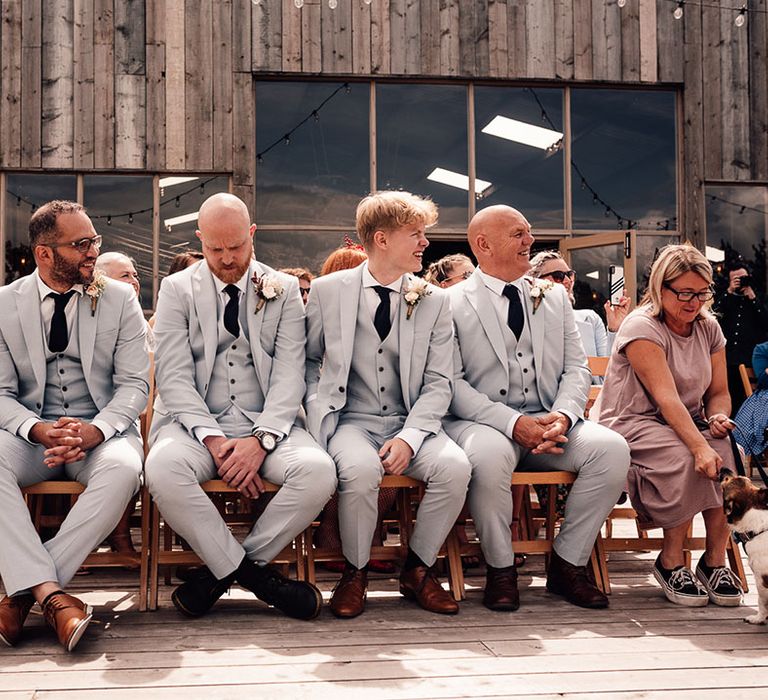 Groomsmen in pale blue wedding suits during outdoor ceremony