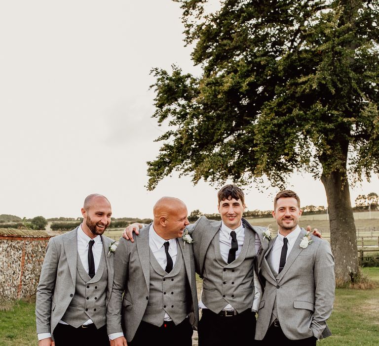 Groom and groomsmen in black trousers with grey jackets and waistcoats for stylish Norfolk barn wedding 