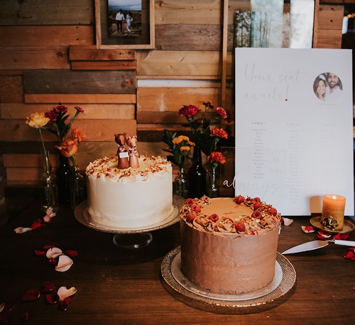 Two single tier wedding cakes rest on a table next to a table plan at an Indian British wedding. 