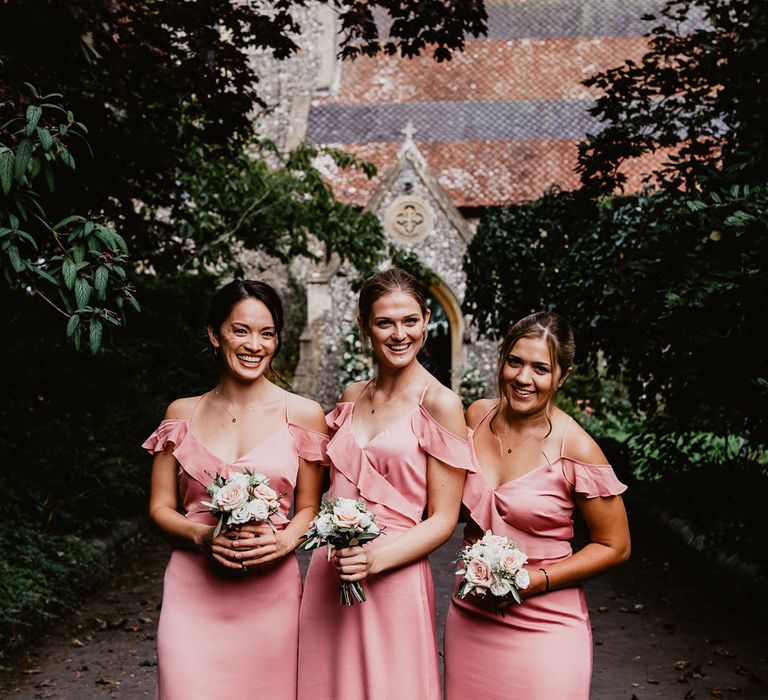 Bridesmaids in pink satin cold shoulder dresses with ruffle trim 