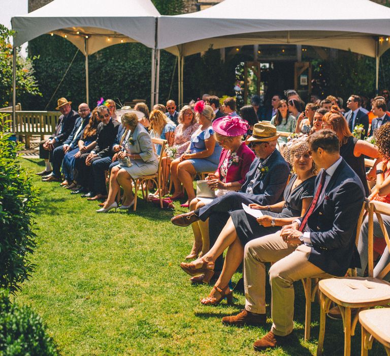 Wedding guests sit outdoors before wedding ceremony begins on sunny summers day | Story + Colour