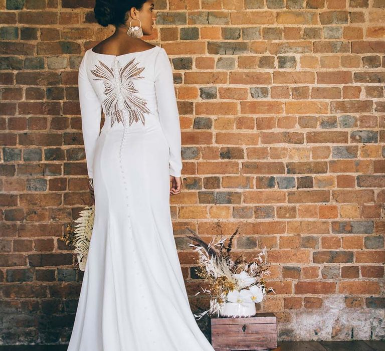 Boho bride with braided up do in a fitted wedding dress with puddle train, button detail and lace cutaway design