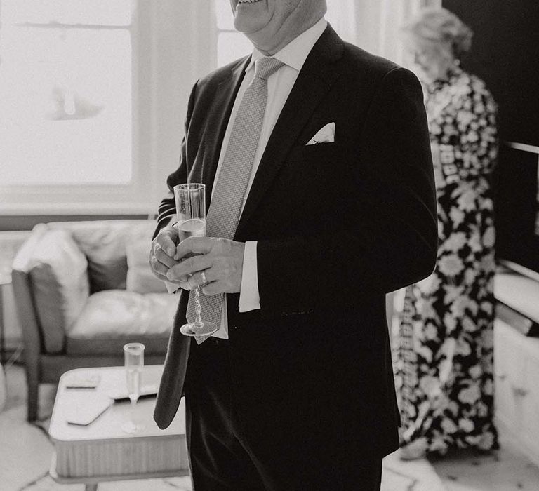 Father of Bride looks at his daughter on her wedding day whilst holding a glass of champagne