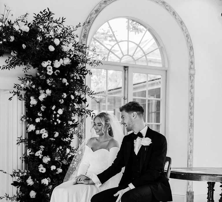 Bride and groom holding hands during the civil ceremony at their black tie Northbrook Park wedding 