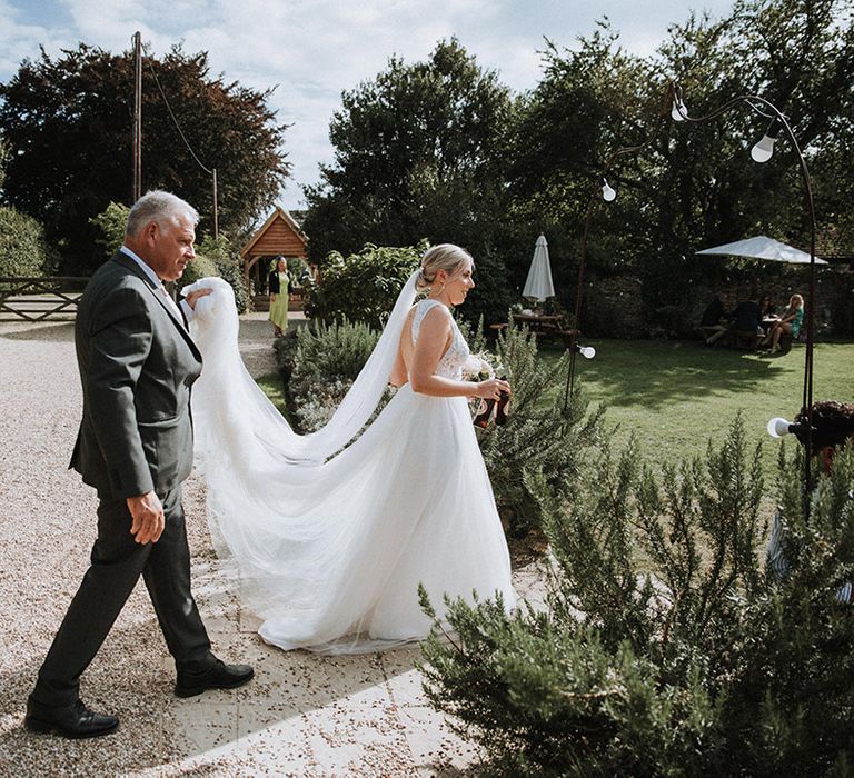 Bride makes her way to ceremony at The Great Tythe Barn wedding venue