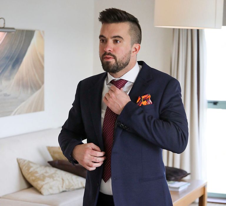 Groom does up his tie on the morning of his wedding day