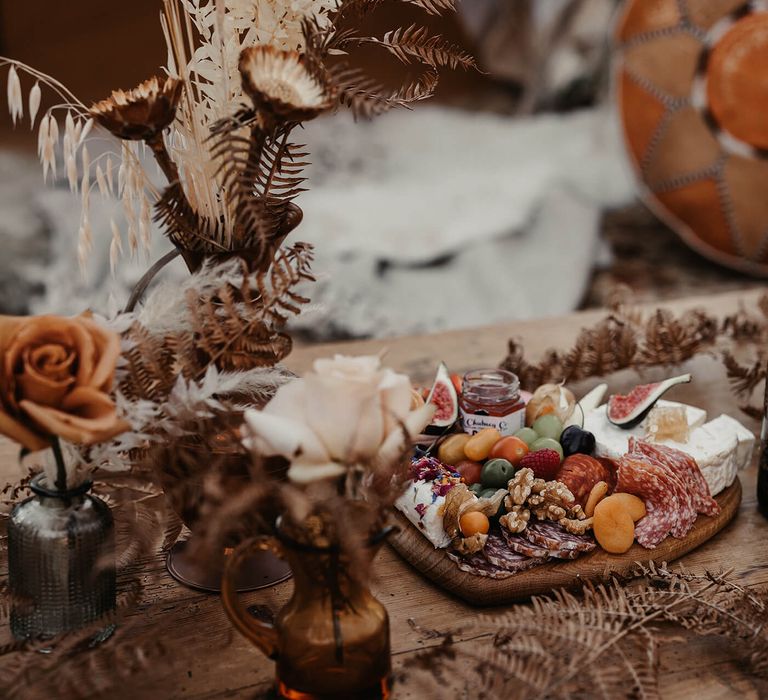 Heart shaped grazing board with cheese and dried flower decor at campsite marriage proposal 