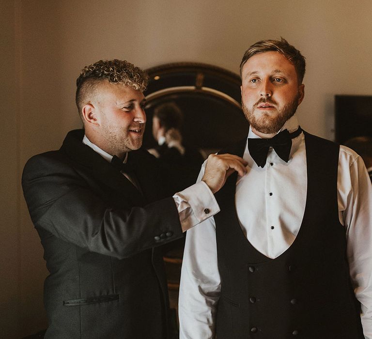 Groom in a horse shoe waistcoat and bow tie on the wedding morning 