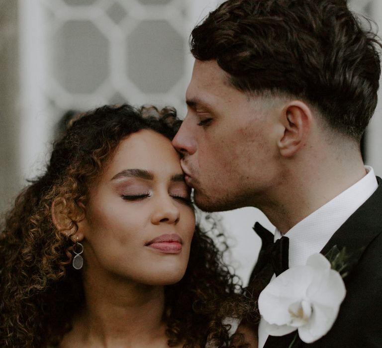 groom kisses the top of brides head on their wedding day