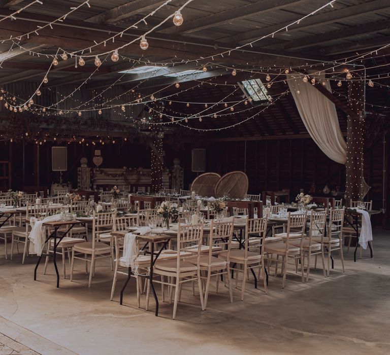 Barn wedding day complete with rustic vibe and fairy lights hanging from ceiling 